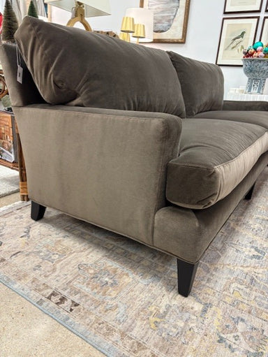 Brown sofa with cushions on a patterned rug in a room setting.