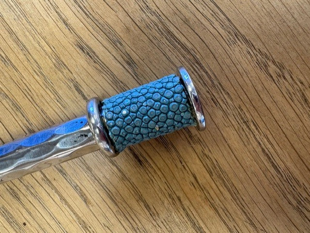 Blue textured handle with silver accents on a wooden surface