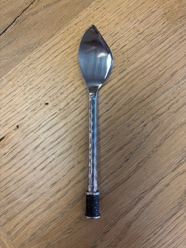 Silver spreader with black handle on a wooden surface