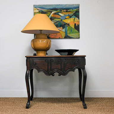antique table with yellow lamp and artwork