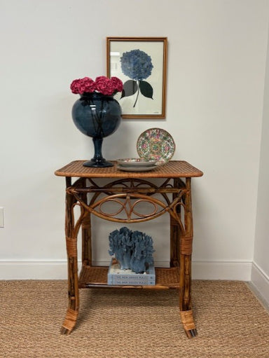 Wicker side table with decorative items against a white wall