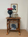 Wicker side table with decorative items against a white wall