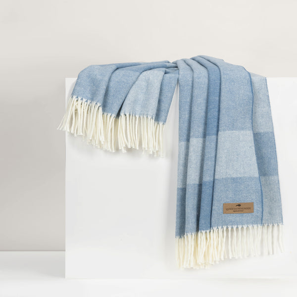 Blue plaid throw with white fringe on a white surface