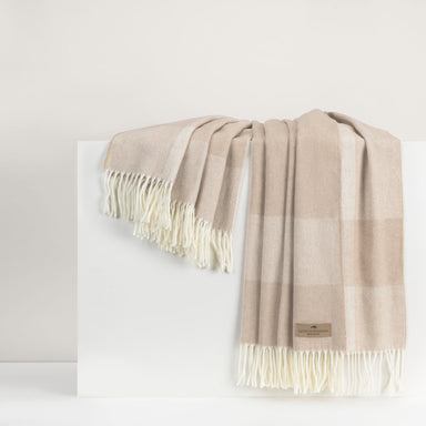 Beige and white checkered throw with fringes on a white background