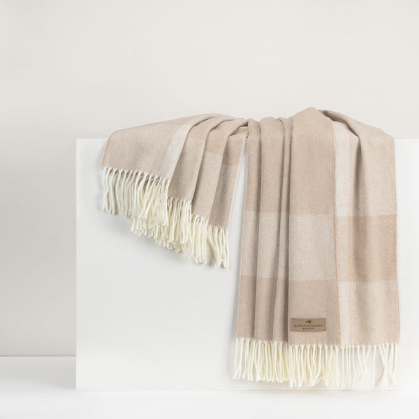 Beige and white checkered throw with fringes on a white background