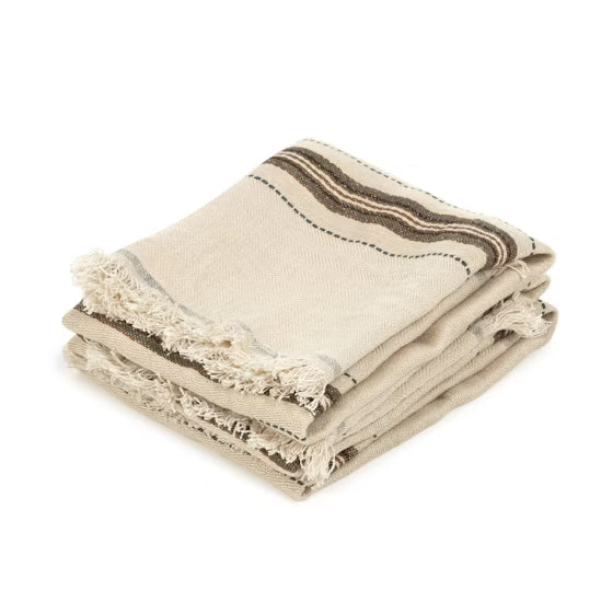 Folded beige towel with brown stripes and fringes on a white background