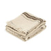 Folded beige towel with brown stripes and fringes on a white background