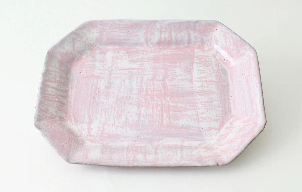 A rectangular ceramic serving platter with rounded corners and a distressed, hand-painted pink and white glaze, shown from a top-down view on a white background.