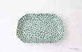 Rectangular ceramic plate with green dot pattern on a white background