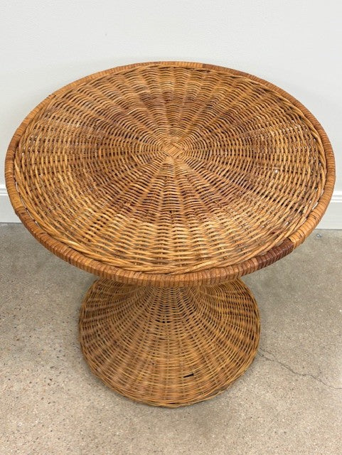 Wicker side table on a concrete floor with a white wall background