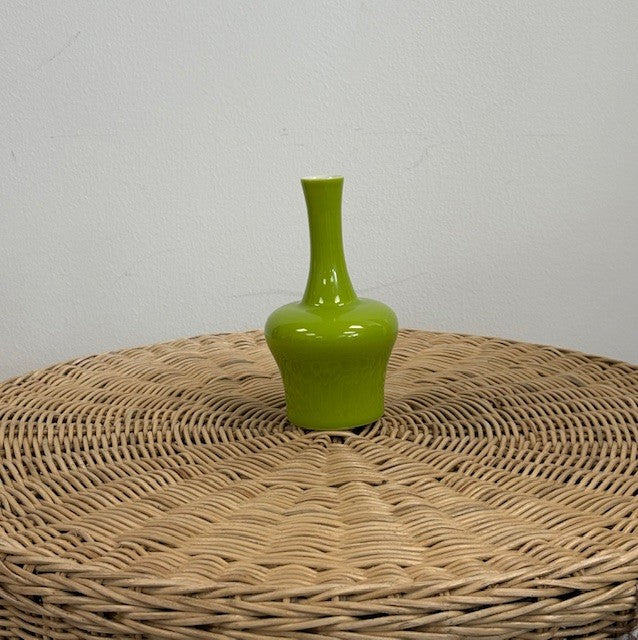 Green vase on a woven surface with a plain background