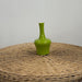 Green vase on a woven surface with a plain background