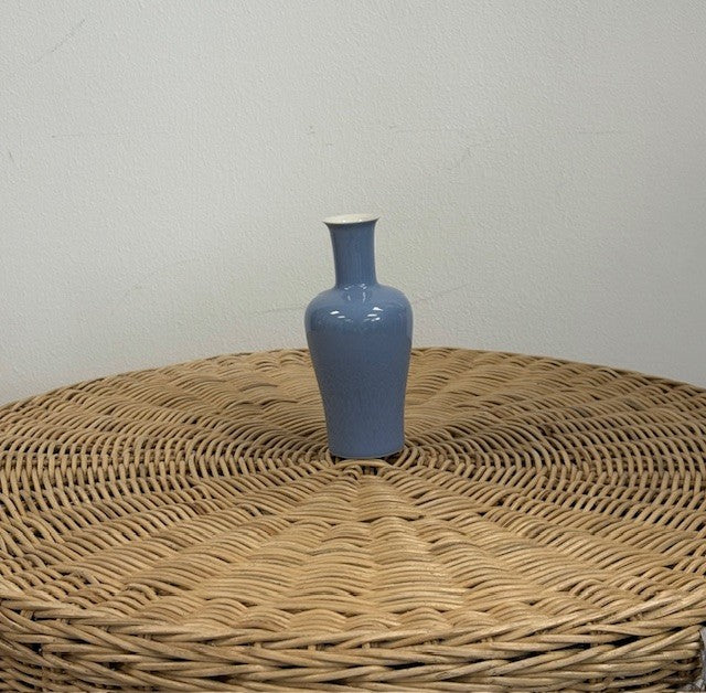Blue vase on a woven surface with a plain background