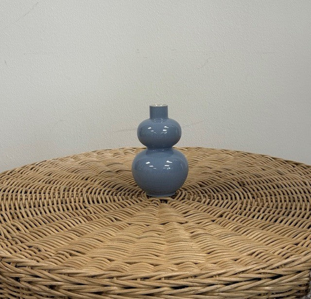 Blue ceramic vase on a wicker surface with a plain background