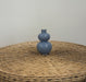 Blue ceramic vase on a wicker surface with a plain background