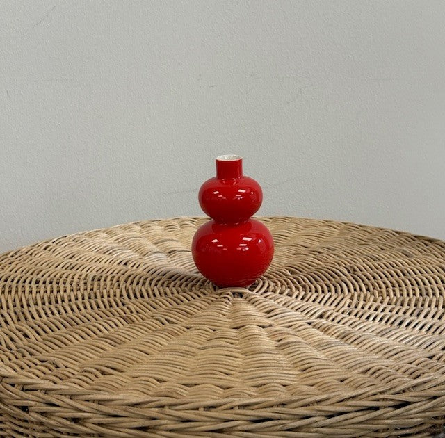 Red double-gourd vase on a wicker surface with a gray background