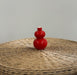 Red double-gourd vase on a wicker surface with a gray background