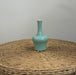 Light blue ceramic vase on a wicker surface with a plain background