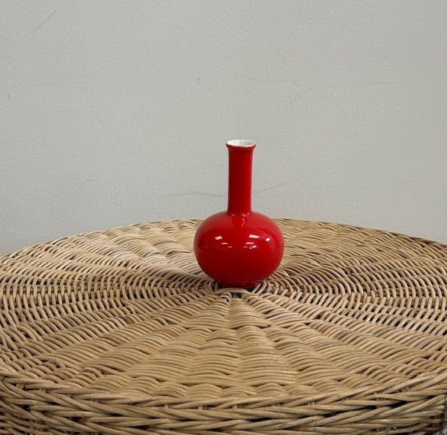 Red vase on a textured surface with a plain background