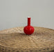 Red vase on a textured surface with a plain background