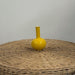 Yellow vase on a wicker surface with a plain background