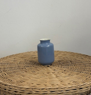 Blue vase on a woven surface with a plain background