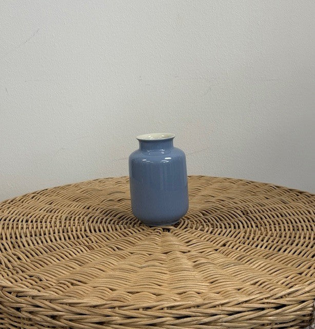 Blue vase on a woven surface with a plain background
