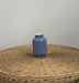 Blue vase on a woven surface with a plain background