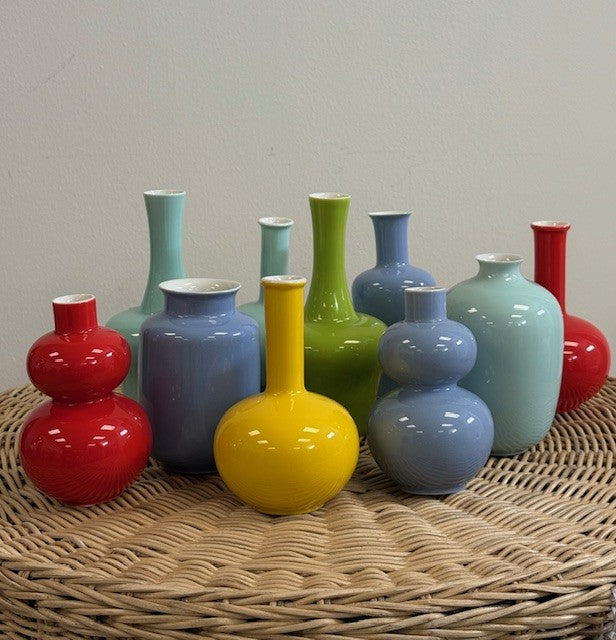 Colorful vases on a woven surface with a plain background