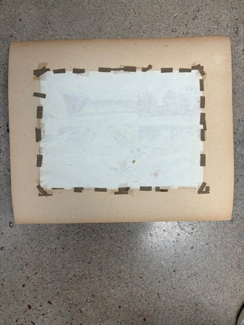 Rectangular object with a white center and brown border on a gray surface