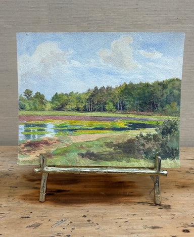 Painting of a landscape with trees and water on an easel.