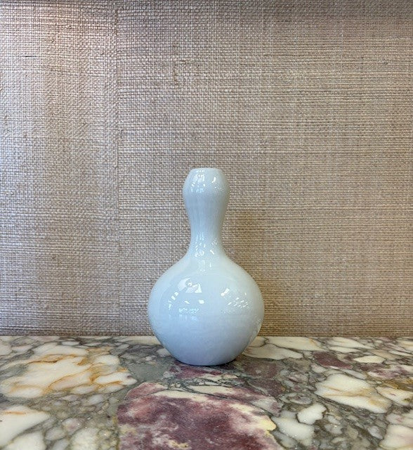White ceramic bottle on a marble surface with a textured wall background