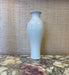 White ceramic vase on a marble surface with a textured wall background