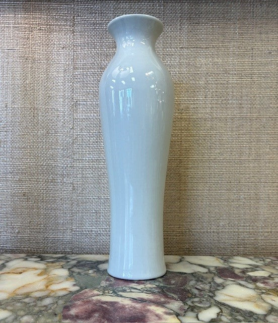 tall White ceramic vase on a textured surface with a neutral background