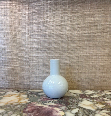 White ceramic bottle on a marble surface with a textured wall background