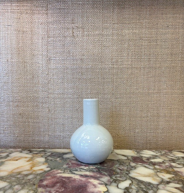 White ceramic bottle on a marble surface with a textured wall background