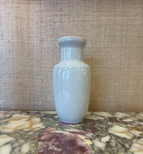 White ceramic vase on a marble surface with a textured wall background