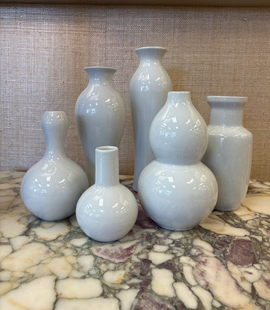 Set of white porcelain vases on a marble surface with a textured wall background