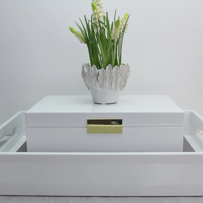 White decorative box with a gold handle and a white vase with greenery on top against a light gray background