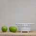 white china basket in front of grasscloth
