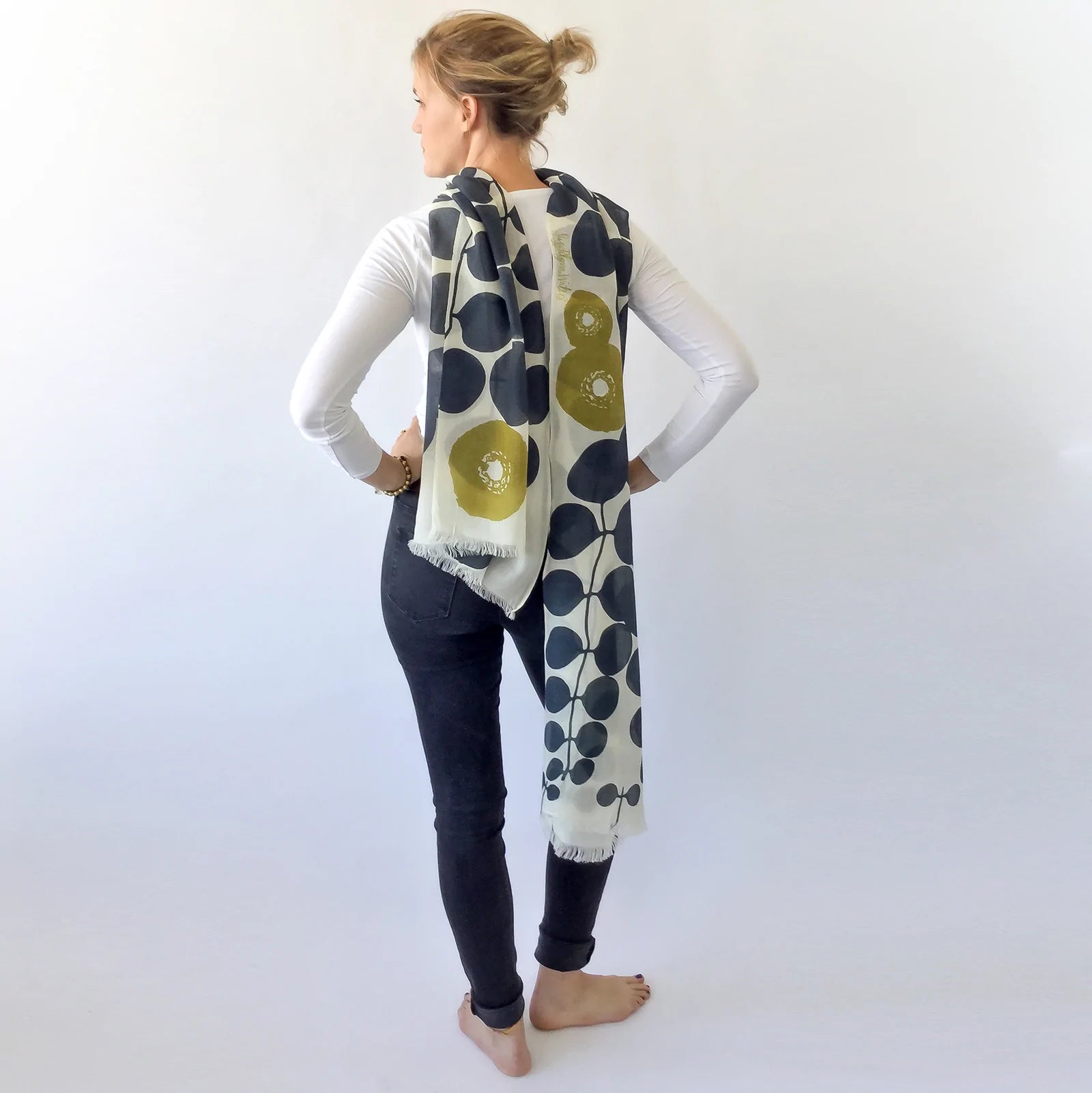 woman showing off black, cream and green merino wool scarf