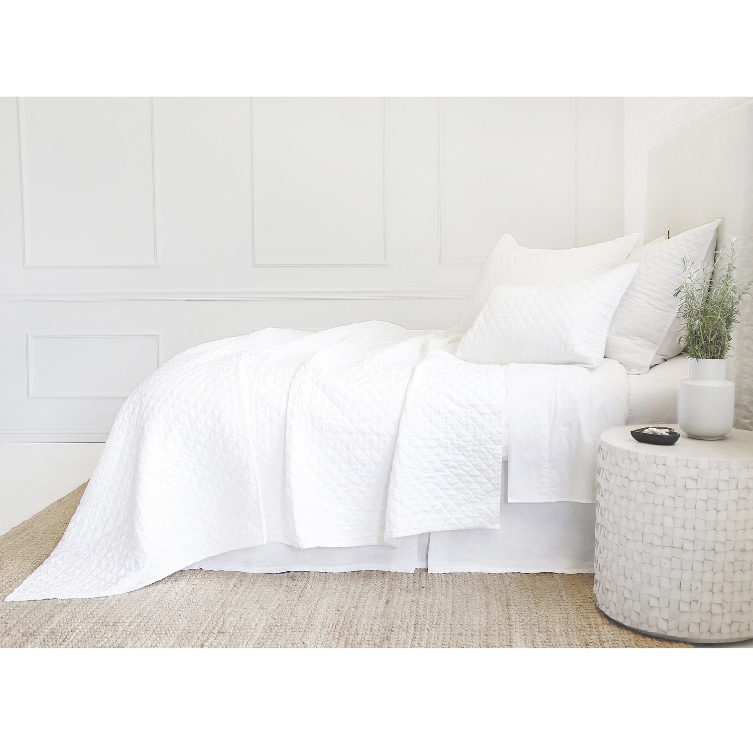 side view of white quilted coverlet and shams on bed