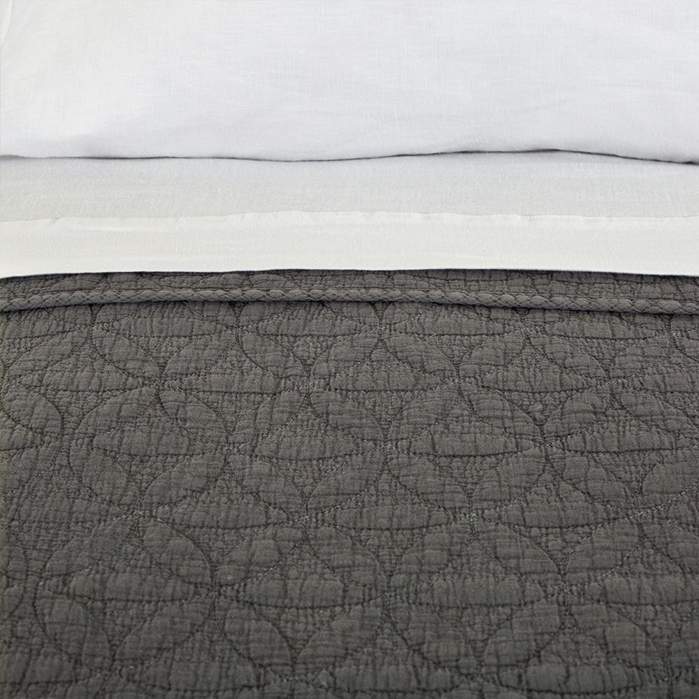 quilted gray coverlet with white sheets