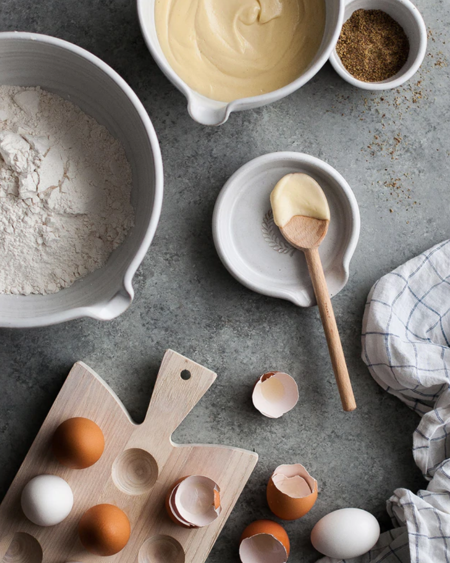 baking scene with mixing bowls, egg tray and spoon rest