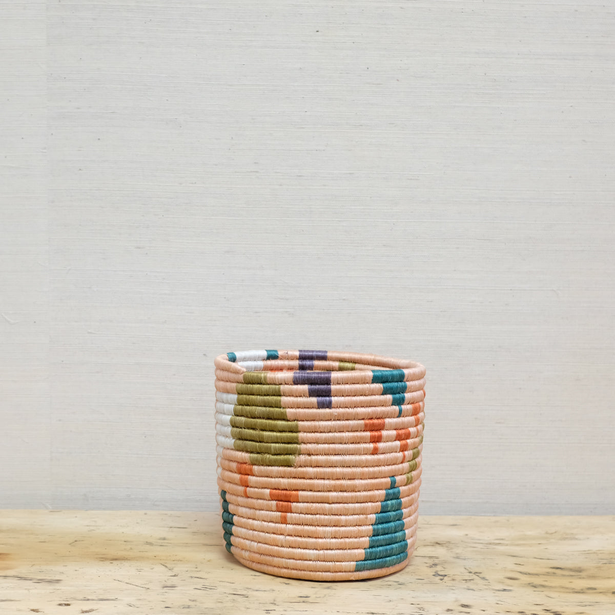 handwoven planter basket in peach, teal and orange geometric pattern