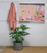 pink and black abstract art hanging on the wall next to a pink coat and plant