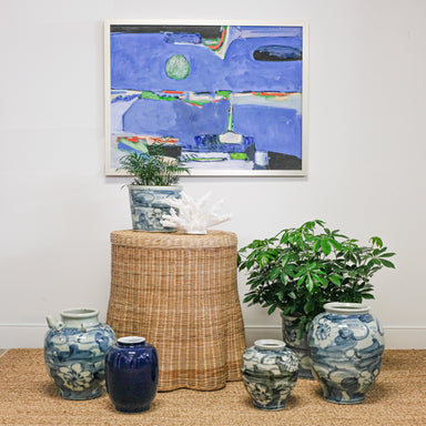abstract artwork behind collection of blue and white pottery with plants and coral