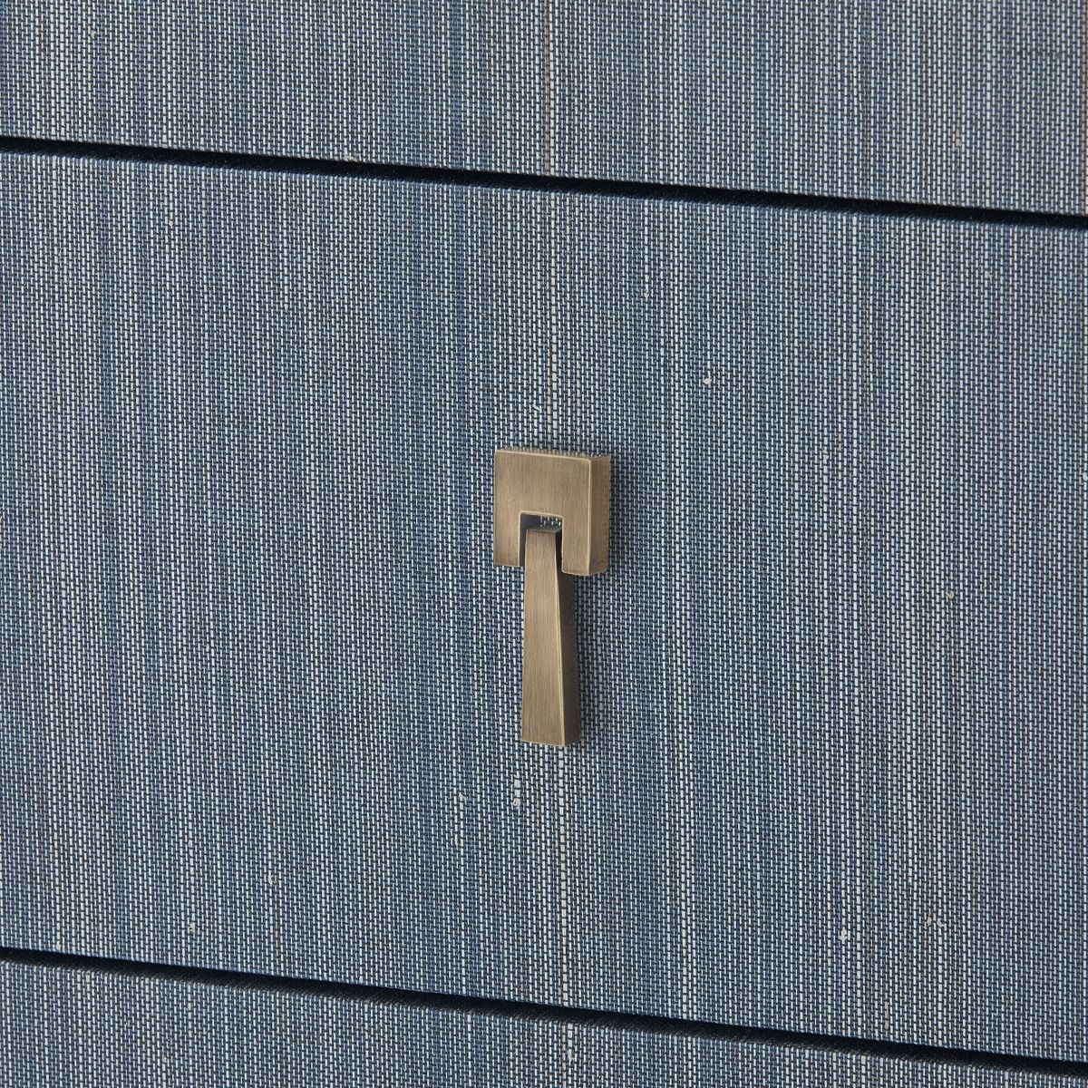 brass pull detail on blue grasscloth-covered chest of drawers