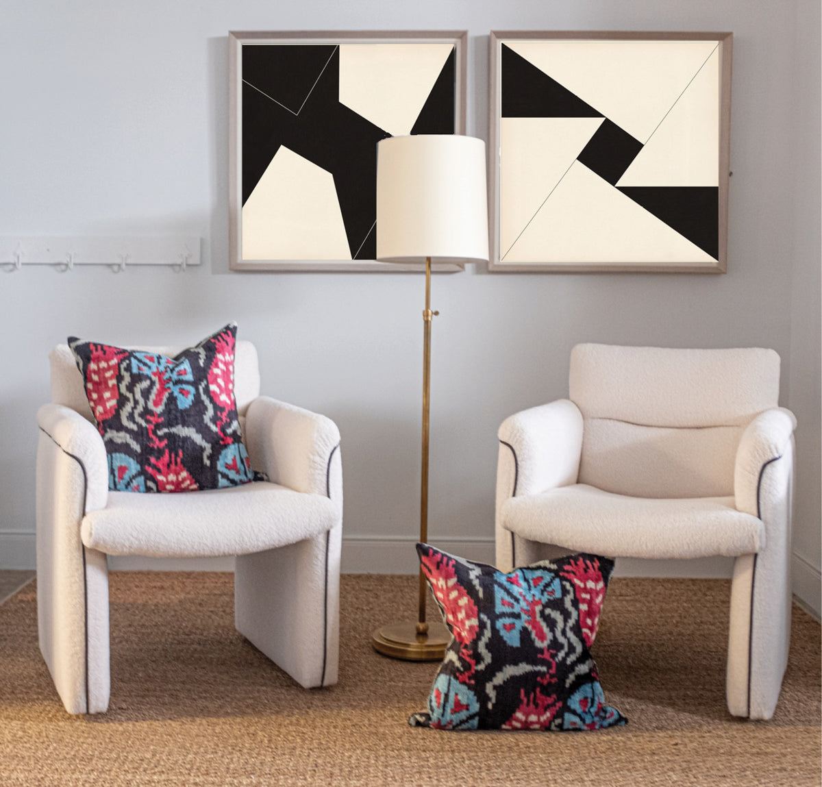 pair of vintage chairs underneath black and white artwork and a floor lamp
