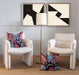 pair of vintage chairs underneath black and white artwork and a floor lamp